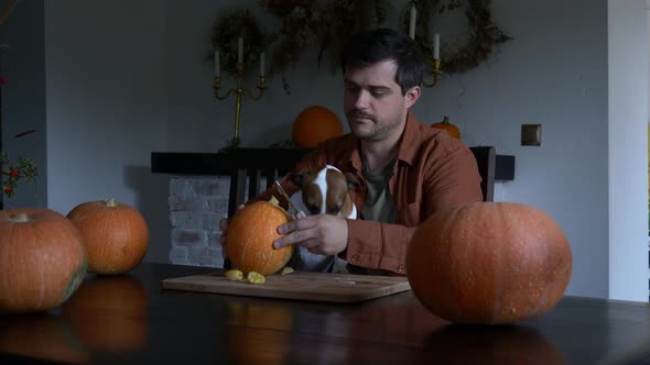 Man with a dog preparing pumpkin for a Halloween