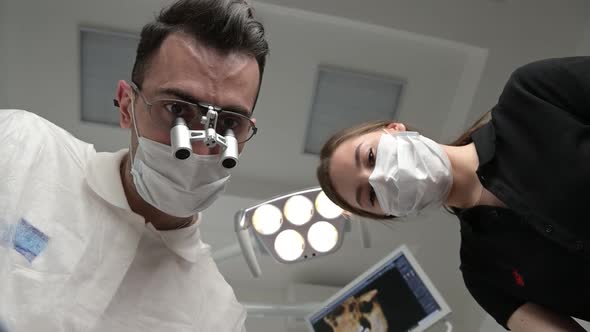 Dentist and assistant work with a patient, first-person view.