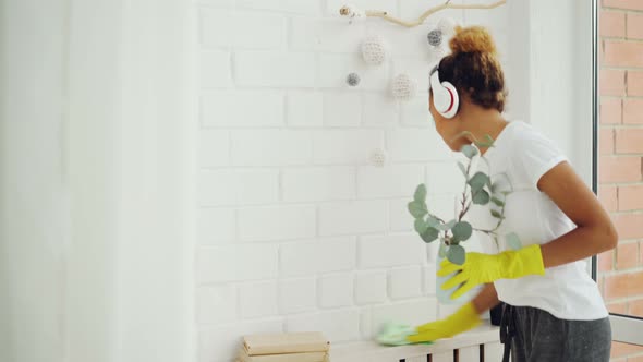 Cheerful Maid African American Girl Is Doing Housework Dusting Using Cloth and Wearing Gloves, Young