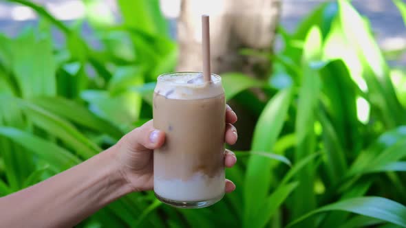 Human Hand Holding Iced Latte Macchiato on Coffee Break Outside Tasty Freshness and Energy Ecostraw