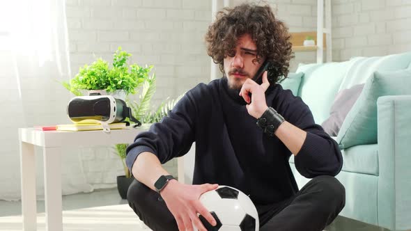 Man Standing with Soccer Ball in Hands and Talking on the Phone