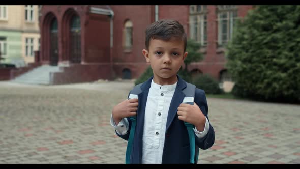 Portrait of Young Boy with Backpack Turning Head and Looking To Camera. Crop View of Kid in School