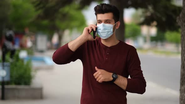 Male wearing a medical mask using the smartphone