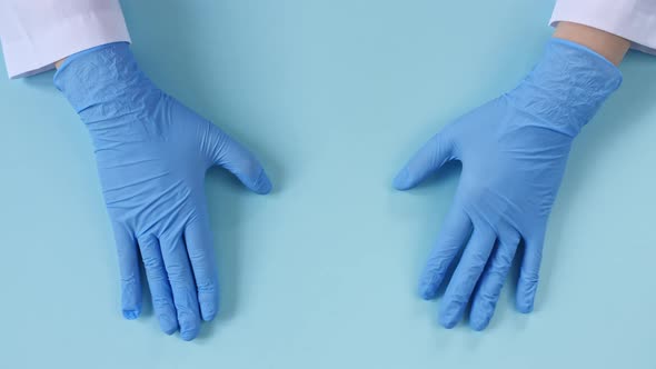 Doctor's Hands in Medical Gloves Making Shape of Heart on Blue Background with Copy Space