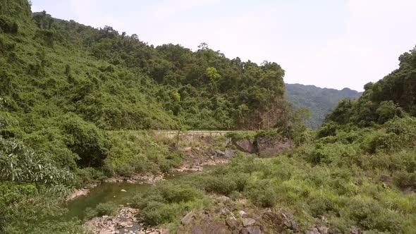 Small Narrow Mountain River Curves Among Green Thick Trees