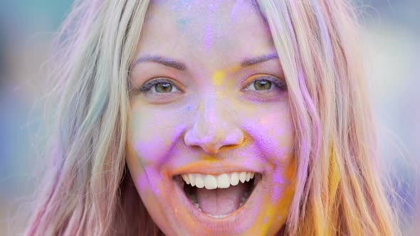 Playful Girl Painted in Colorful Powder Smiling and Posing for Camera, Closeup