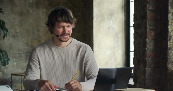 Serious Young Caucasian Man Speaking By Video Call and Looking at Laptop