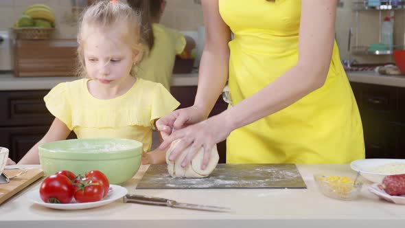 Children Watch As Mom Cook Mixes Pizza Dough Close-up. Woman's Hands Knead the Dough.