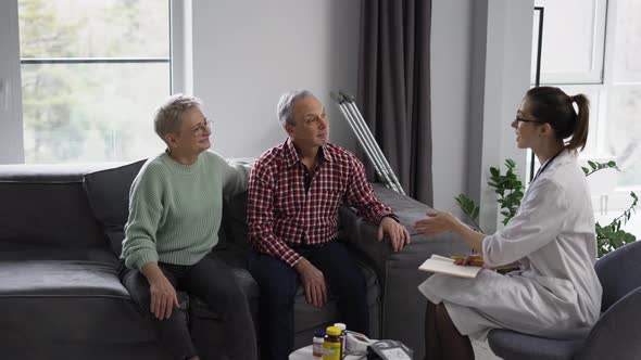 Doctor Talking with Senior Couple at Home or Nursing Home
