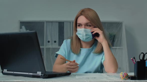 Girl Wearing Face Mask Using Computer and Speaking Mobile Phone Closeup View