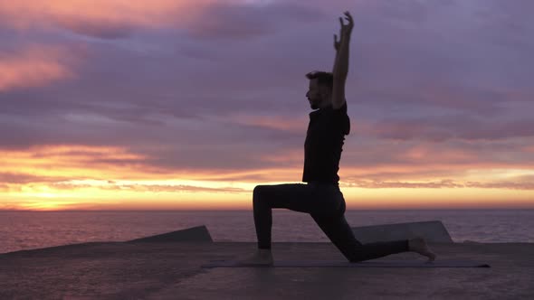 Young Athletic Man Performing Yoga Pose in Front of the Ocean at Sunrise