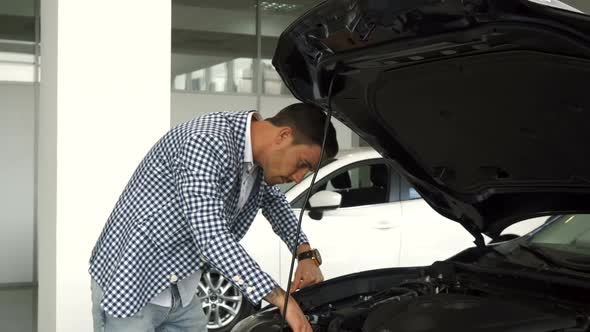 The New Owner of the Car Studies the Details in an Open Hood