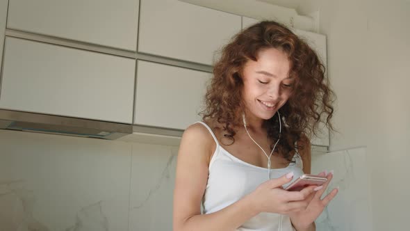 A Young Woman is Listening to Music with Headphones on and Laughing