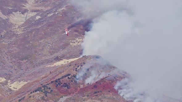 Airplane dropping fire retardant in wildfire path on Timpanogos Mountain