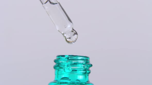 A Drop of Essential Oil Falls From the Pipette Into the Cosmetic Bottle Macro
