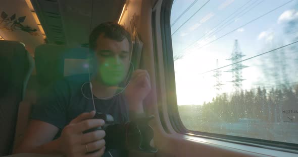 Man in train shooting footage and looking out the window