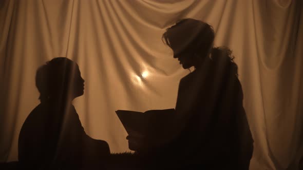 Silhouettes of Woman and Boy Reading a Book of Fairy Tales