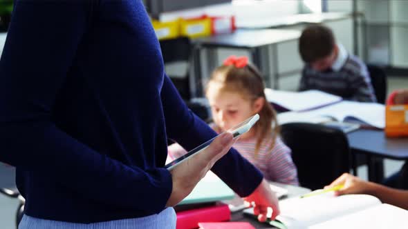 Teacher using digital tablet while teaching in classroom