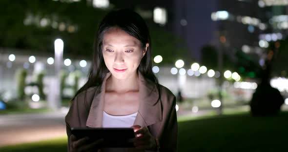 Woman sending message on cellphone in city at night