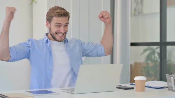 Successful Young Creative Man Celebrating on Laptop at Work