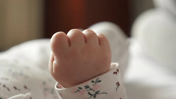 Tiny Hand of Newborn Baby Clenched Into Fist in Bedroom