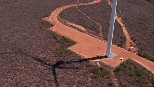 Rotating wind turbine shadow. Aerial tilt up revealing field with wind turbines