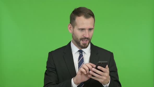 Cheerful Businessman Getting Excited While Using Cellphone Against Chroma Key