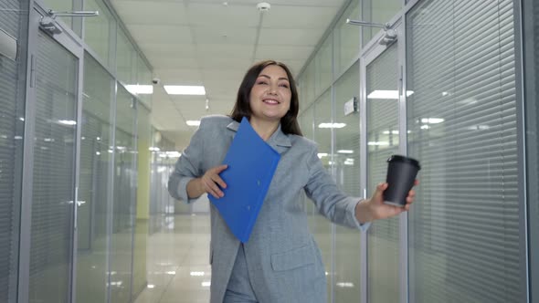 Joyful Manager in Grey Jacket Walks Along Hall Dancing