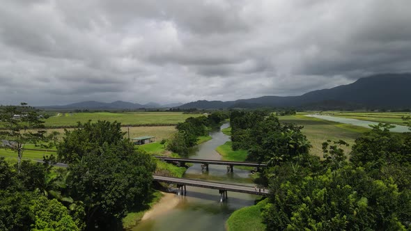 Aerial view looking down at a small country road bridge spanning over a crocodile in infested river