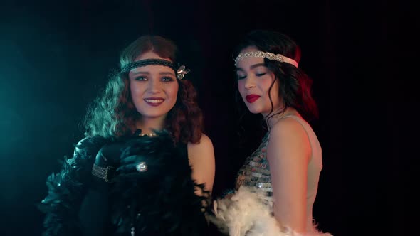 Attractive Flappers Women Dressed in Roaring Twenties Time Dancing on Party in Neon Smoke Room