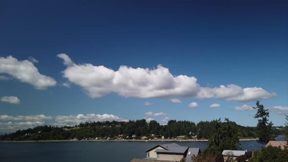 Moving time lapse of rolling clouds in a warm summer day looking over Wollochet Bay and Carr Inlet,