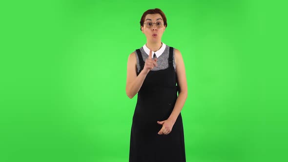 Funny Girl Is Listening Attentively and Nodding His Head Pointing Finger at Viewer. Green Screen