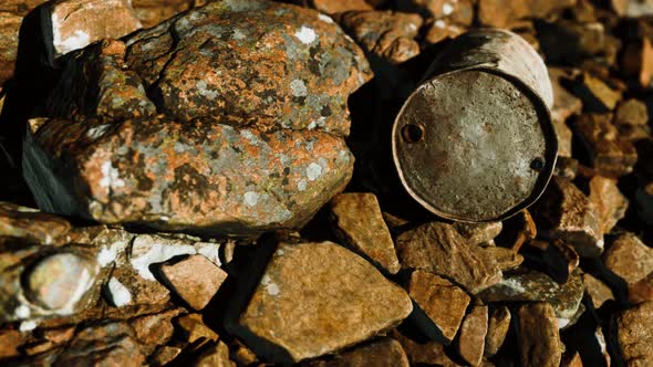 Rusty Destroyed Metal Barrel on Beach Rocks