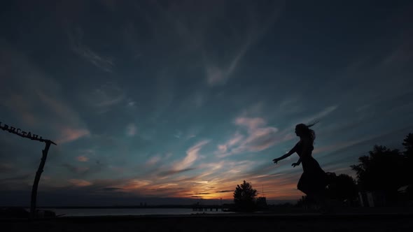 Silhouette of a Ballerina Against the Sunset Sky. Ballerina Makes High Beautiful Jumps