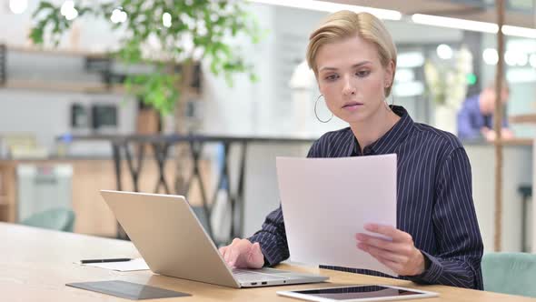 Beautiful Young Businesswoman Working on Laptop with Documents in Office 