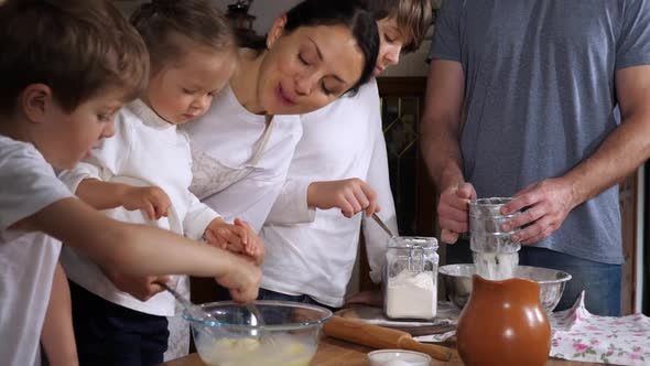 Children Helping Parents to Preparing a Dough in Domestic Kitchen