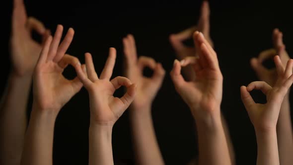 Raising Hands with OK Gestures on Black Background