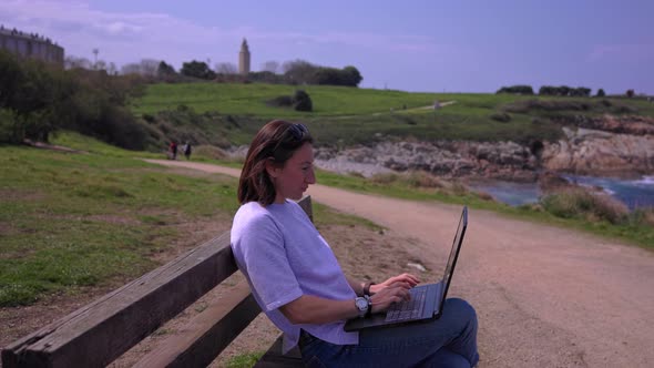 A Girl Near the Ocean Works on a Computer