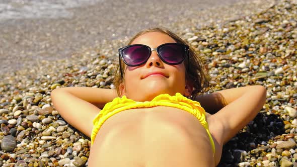 A Child is Sunbathing on the Beach in Sunglasses