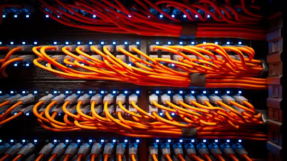 Countless orange cables in a  server cabinet lit by a single spotlight. 4KHD