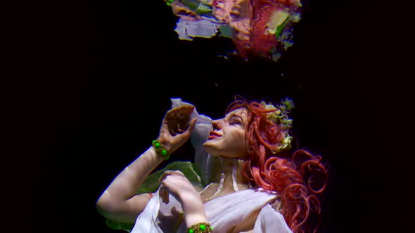 Romantic Young Woman Is Floating Underwater in Black Background and Looking on Her Reflection