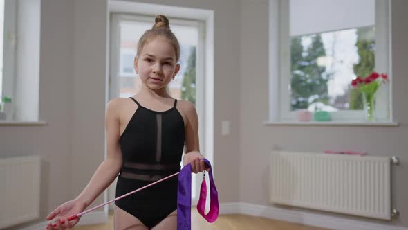 Skilled Brunette Teenage Gymnast Posing with Gymnastic Ribbon Indoors in Slow Motion