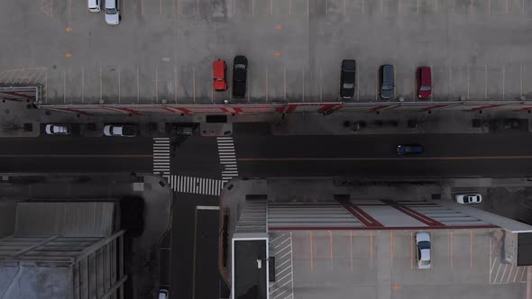 Aerial footage over city flying over town and cars with people and parking garages