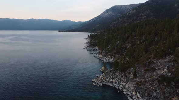 Drone shot of the rocky East shore of Lake Tahoe and the surrounding forest at sunset. This vibrant