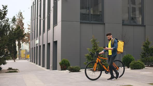 The Food Delivery Guy is Going and Looking at the Smartphone