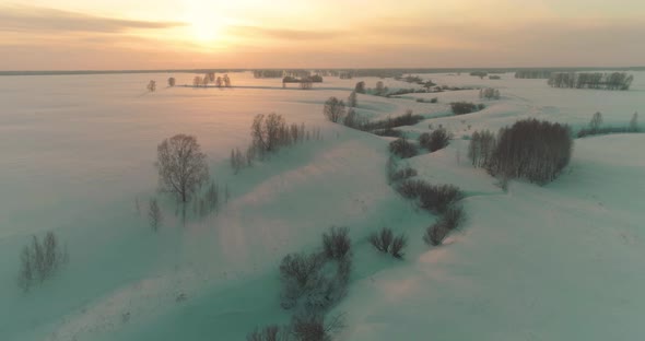 Aerial View of Cold Arctic Field Landscape Trees with Frost Snow Ice River and Sun Rays Over Horizon