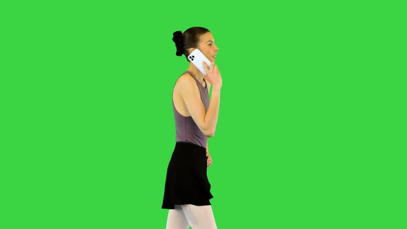 Young Ballerina in Training Clothes Walks Talking on Mobile Phone Hand on Hip on a Green Screen