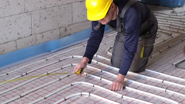 The Worker Lays Pipes for a Heatinsulated Floor