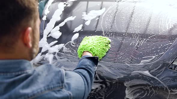 Bearded Man Washing Own Car Using foam Sponge in Outdoors Car Wash