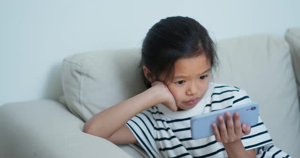 Young girl watch on the cellphone and sit on the sofa